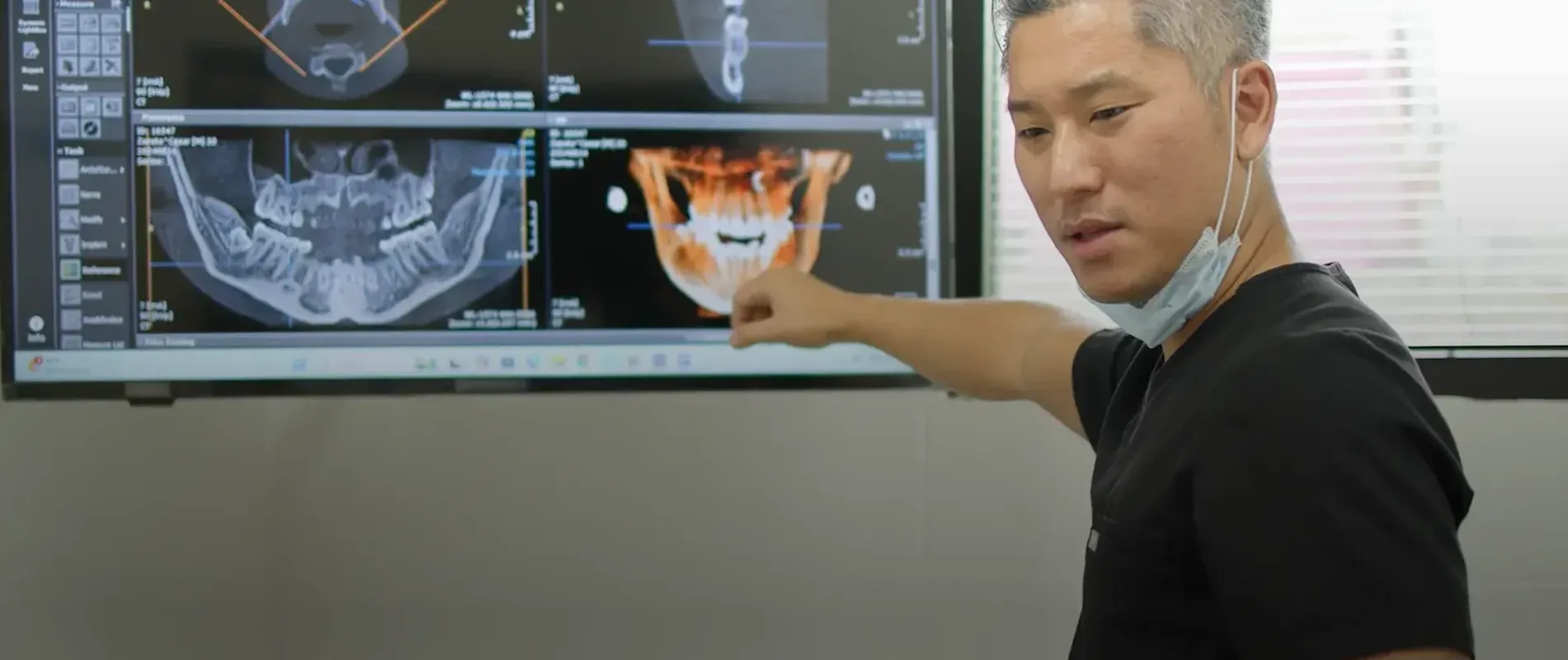 Dr. Andrew Kim pointing to a 3D dental scan displayed on a large monitor.